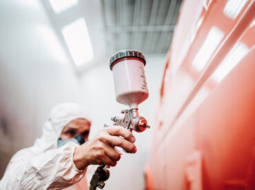 close up of paint spray gun, worker painting a car