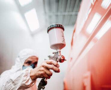 close up of paint spray gun, worker painting a car