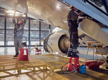 Full length side view portrait of men aviation mechanics fixing and checking spoiler and flaps on the airplane