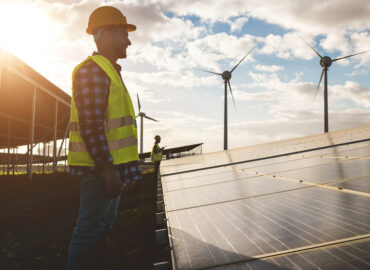 People working for solar panels and wind turbines - Renewable energy concept - Soft focus on man face