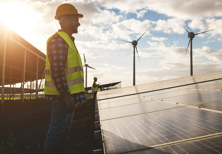 People working for solar panels and wind turbines - Renewable energy concept - Soft focus on man face